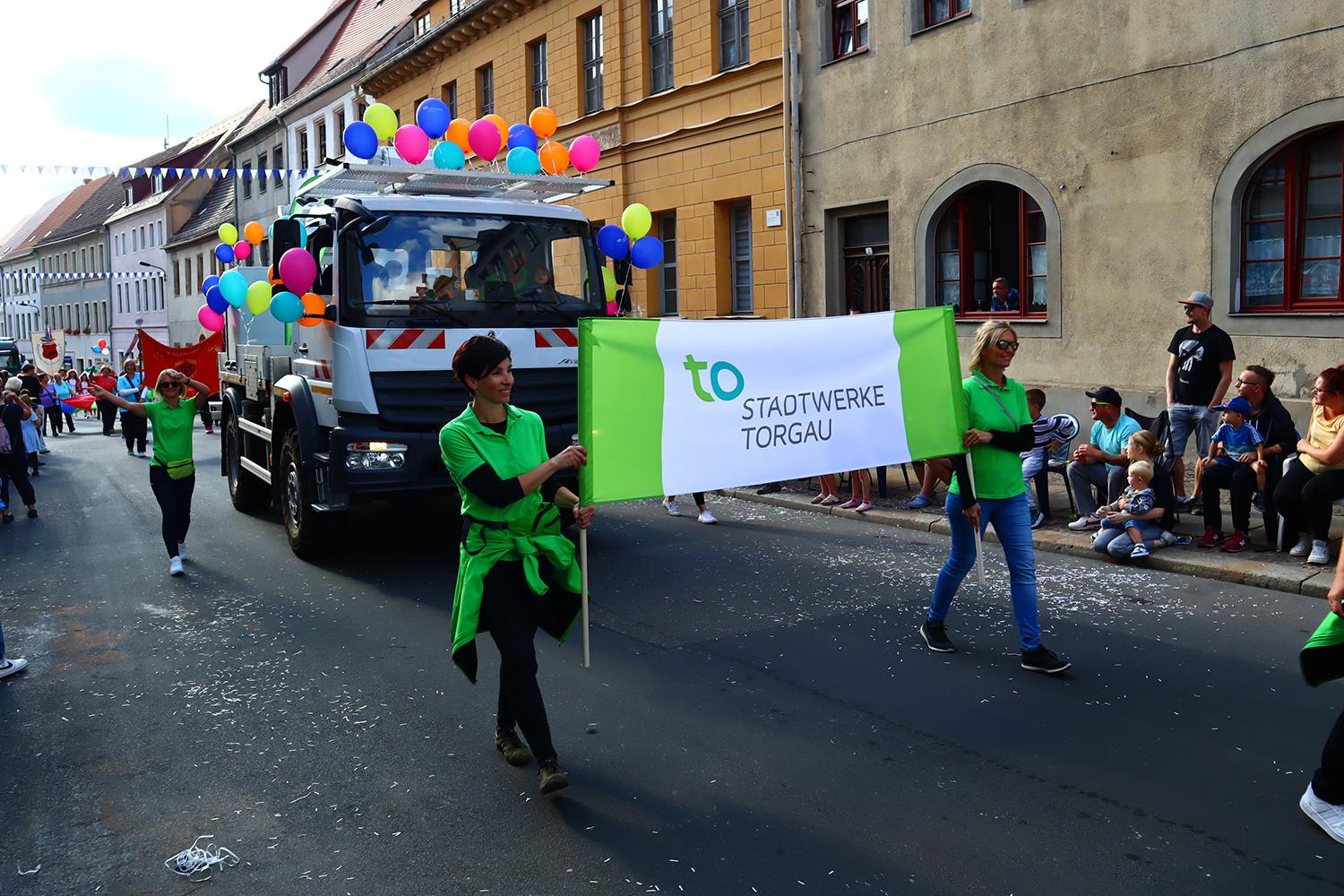 Stadtwerke Torgau Mitarbeiter mit Fahnen und mit bunten Ballons geschmückte Stadtwerke-Fahrzeuge während eines Festumzugs