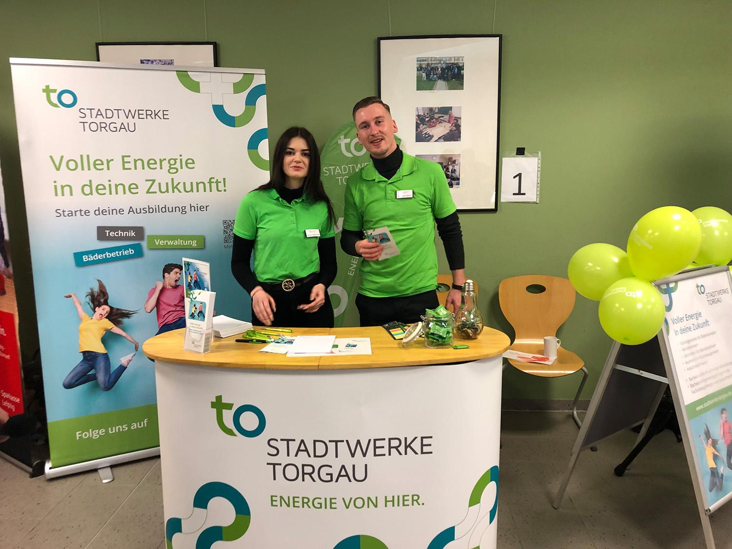 Zwei Mitarbeiter in grünen Stadtwerke Torgau T-Shirts am Messestand der Azubi Expo