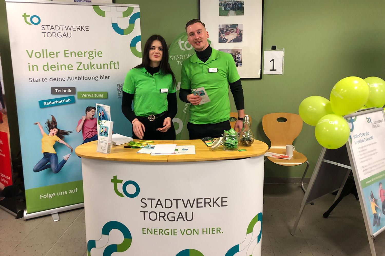 Zwei Mitarbeiter in grünen Stadtwerke Torgau T-Shirts am Messestand der Azubi Expo