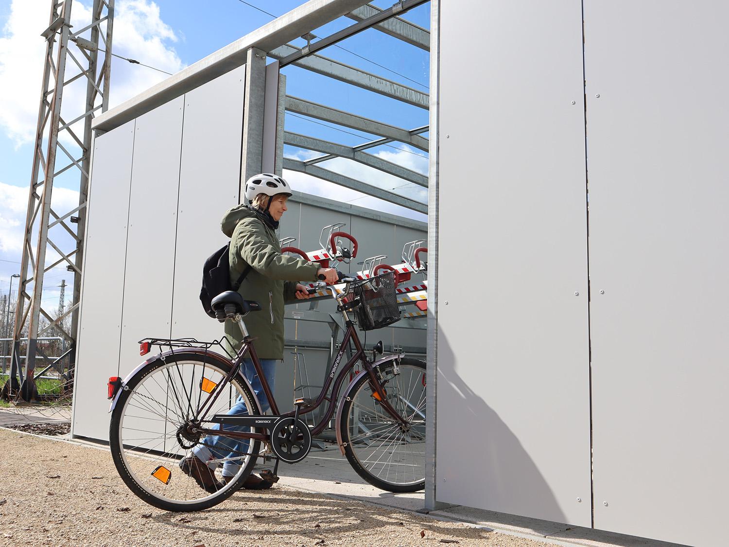 Frau schiebt Fahrrad in Fahrradbox