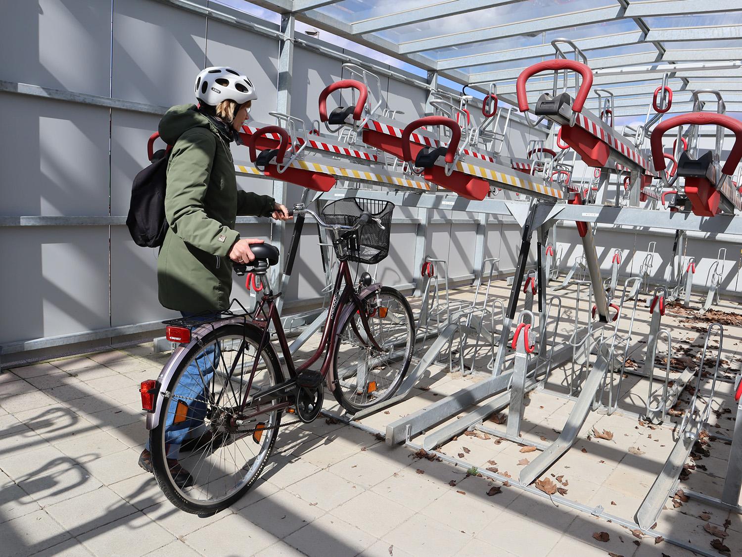 Frau befestigt Fahrrad in Fahrradbox am Bahnhof Torgau