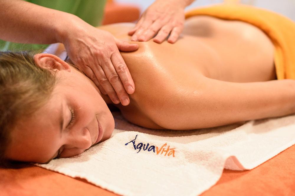 Frau liegt auf Massageliege und bekommt Rückenmassage