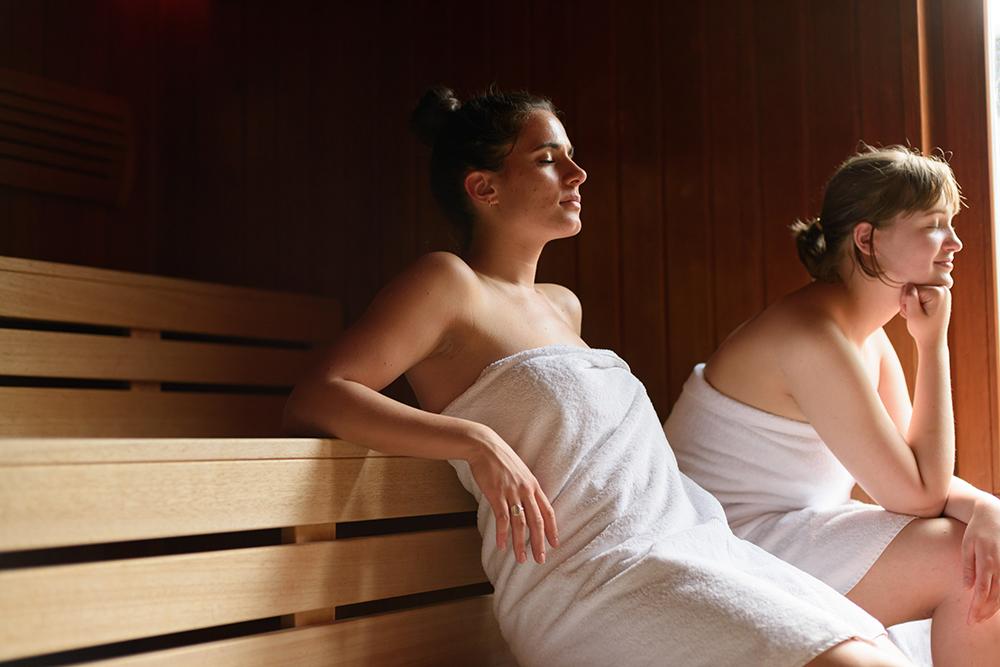 Zwei Frauen genießen in Saunakleidung die Panoramasauna