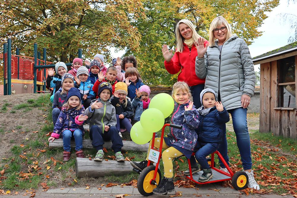 Pressefoto mit Kindergartengruppe, Kitaleiterin und Stadtwerke Torgau Geschäftsführerin Renate Mühlner während Dreirad-Spendenübergabe