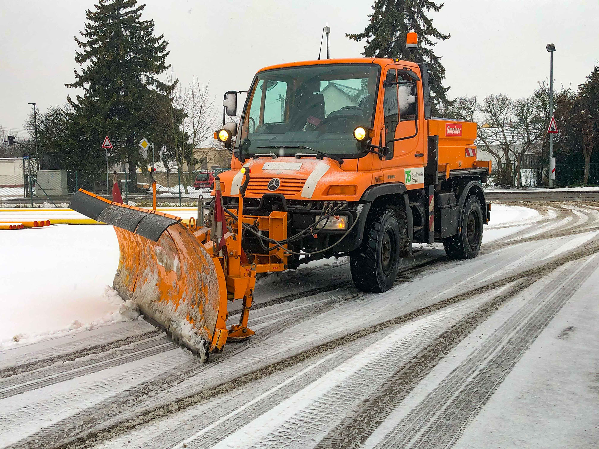 Winterdienst mit Schneepflug auf verschneiter Straße